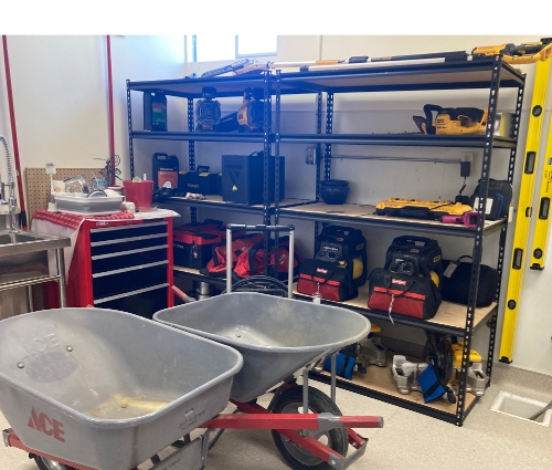 A room with tools on the shelves and wheelbarrows in the foreground